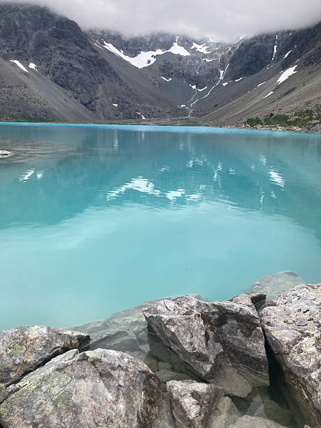 istock Turquoise alpine lake surrounded by rocky mountains and blue sky 2226451888