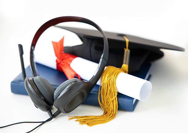 Online education concept. Headphones, graduate cap along with a diploma and a textbook on a white background.