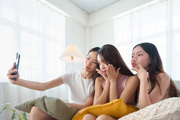 istock Three Asian women posing with playful expressions while snapping a selfie with smartphone, capturing female friendship. 2226455879