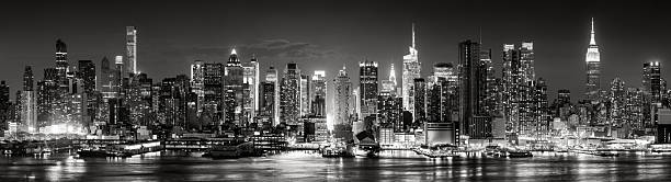 istock Elevated black and white panoramic view of Midtown Manhattan skyline at night with skyscrapers, Times Square lights, and reflections on the Hudson River. New York City, USA 2226456033