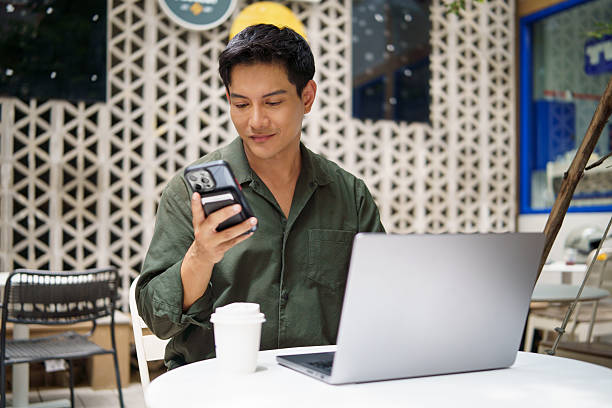 istock Smiling businessman using smartphone while working on laptop at an outdoor cafe. 2226456177