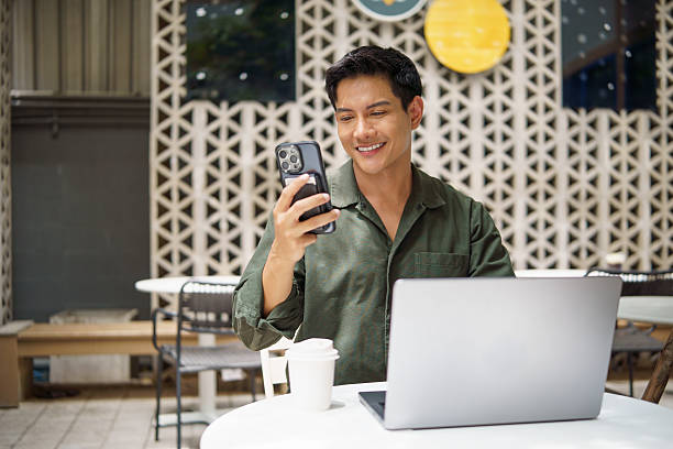 istock Confident professional using mobile phone and laptop simultaneously in a modern outdoor setting. 2226456182