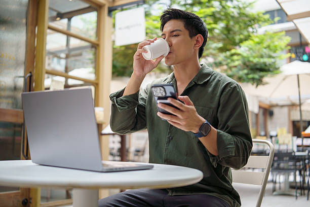 istock Businessman sipping coffee and  checking phone while working remotely at outdoor cafe. 2226456215
