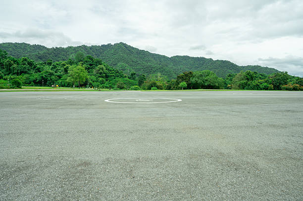 istock Empty helicopter landing pad with asphalt with green mountain forest background providing emergency medical transport access to remote wilderness areas. Helipad platform at dam infrastructure site. 2226456373