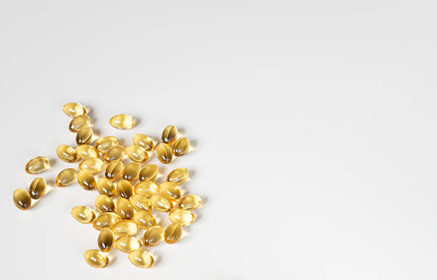 istock Scattered Golden Softgel Pills on White Surface 2226456405