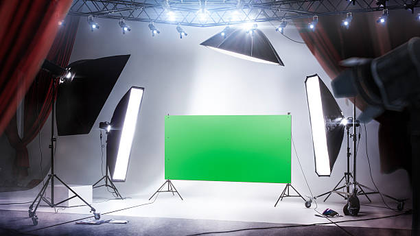 istock Photo studio background with green screen and backlight. professional lighting. Workspace interior with grey backdrop, backstage and lamps 2226458575