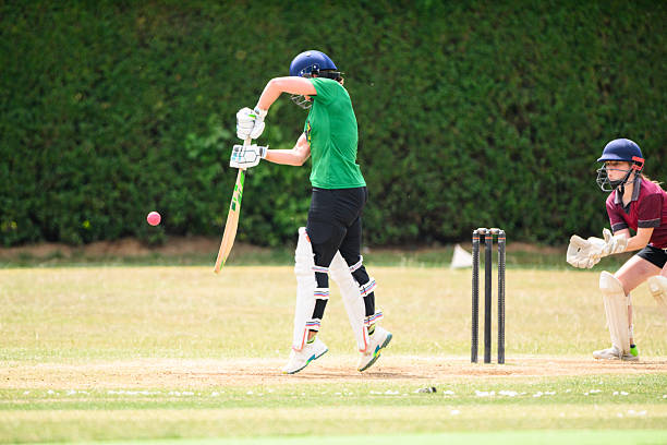 istock Side view middle age female batsman hitting cricket ball, wicketkeeper ready to catch 2226460169