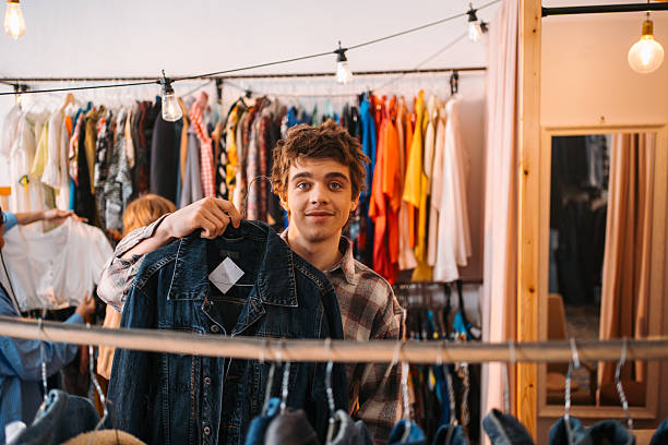 istock A young man confidently holding a stylish jacket while inside a trendy clothing store 2226466377