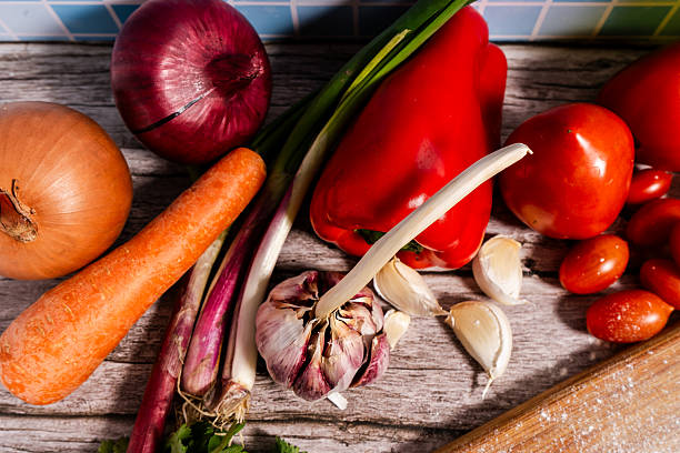 Vibrant vegetables, aromatic herbs, and pungent spices arranged on a rustic wooden table, ready for cooking