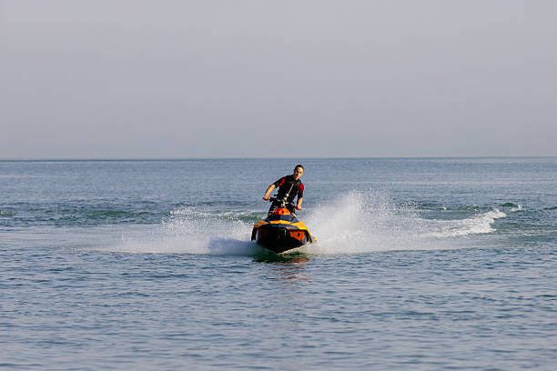 Young man rides a jet ski across turquoise waters during seaside vacation. Concept water sports passion and active leisure
