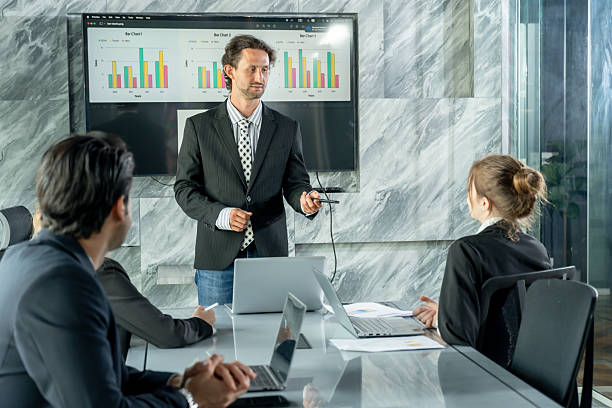 istock Caucasian male manager standing front meeting screen explaining company performance to multiracial business team during office meeting with charts graphs laptop teamwork strategy 2226469895