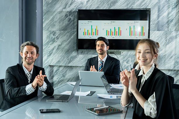 istock Multiracial business team smiling and applauding inside office after project success, team members expressing support and appreciation during meeting with financial reports and laptop on table 2226470128