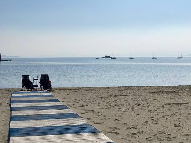 Rear view of two women sitting on adirondack chairs and watching seascape