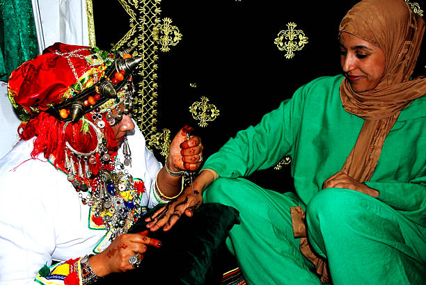 Amazigh female artist  applying a traditional Henna tattoo on a female hand. This is part of a large showcase of cultural arts of the Desert that takes place every year during the Moussem Festival of Tan Tan in Southern Morocco.