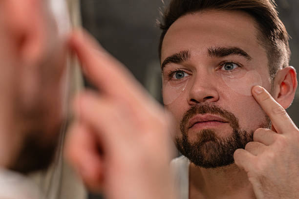 istock Man applying under eye patches in front of a bathroom mirror 2226476750