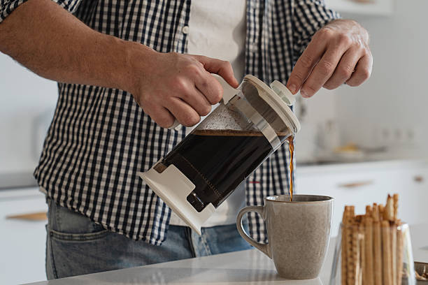 istock Man  pouring coffee from a French press into a mug in a bright kitchen 2226479252