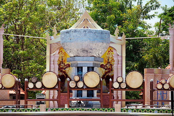 Arranged group of big thai drums outdoors on square near a park in Lampang for local thai art and music performance in classic styles with drums. Park is Kelang Nakhon Public Park. In center is a large bowl.
