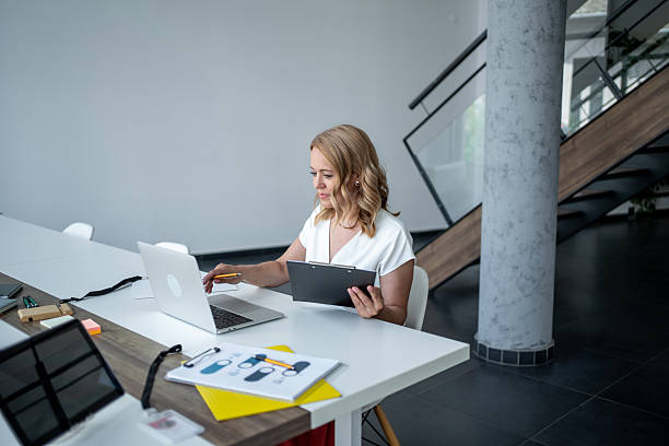 istock Businesswoman working on laptop and taking notes in modern office 2226484364