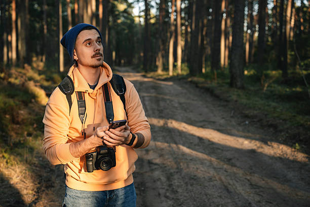 istock Man Using Smartphone GPS for Navigation in Forest with Camera Gear 2226485450