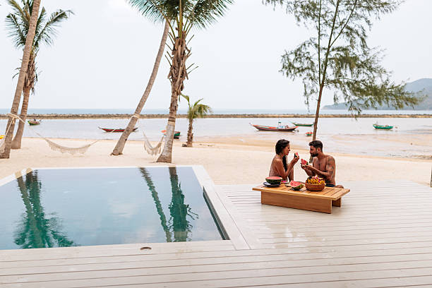 istock Smiling couple enjoying watermelon by the pool 2226485557