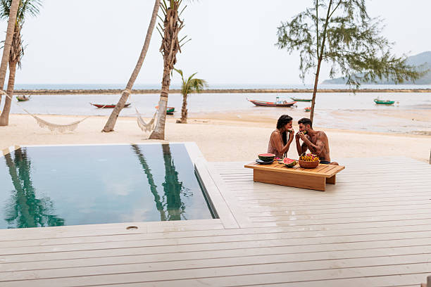 istock Smiling couple enjoying watermelon by the pool 2226485587