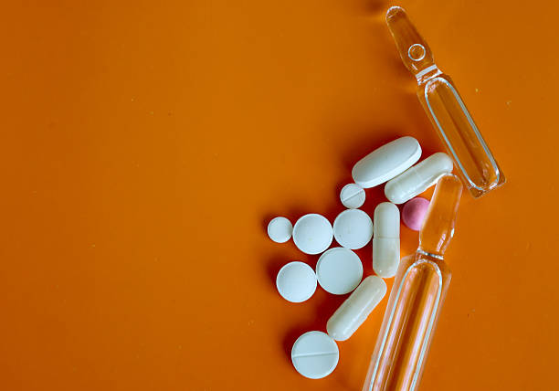 istock Medical ampoules and various pills, arranged on an orange background, create a visualization of pharmaceuticals. 2226486545