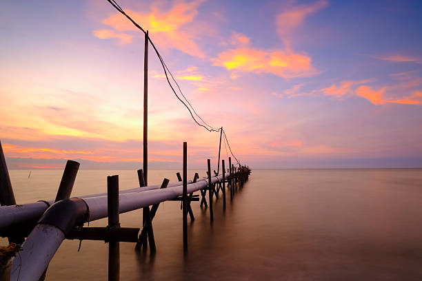 Pipeline stretching into the calm ocean at sunset