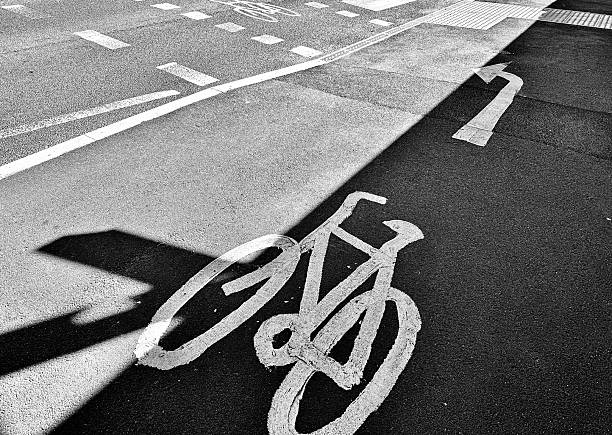 A cycle lane and direction arrow on asphalt with the sun casting shadows on the road