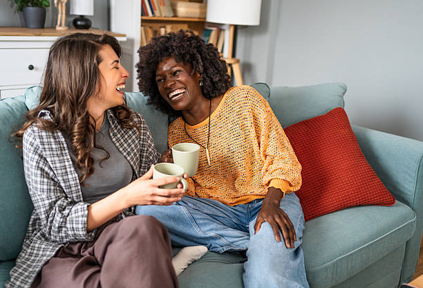istock Two female friends laughing and drinking tea on sofa at home 2226496179