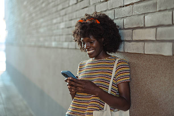 istock Woman smiling at phone while leaning against brick wall 2226497646