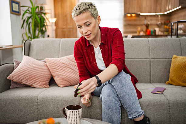 istock Woman adding cbd oil to her tea while relaxing on the sofa at home 2226498510