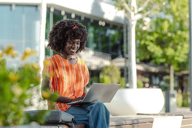 istock Young woman working on a laptop outdoors in a modern urban setting 2226500172
