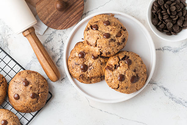 istock Fresh chocolate American chip cookies with nuts and chocolate drops on white marble background. Flat lay of cookies with stylish cutlery and pastry chef accessories. Recipe of homemade cookies concept 2226501198