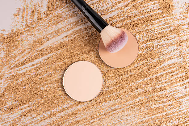 istock Two round blocks of compact powder refills in different tones lie on a beautiful background of spilled powder texture with a fluffy makeup brush. 2226507788