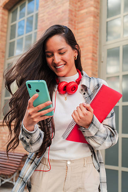 istock Vertical. One latina student using her smartphone to share on the social media app. Hispanic teenager having fun with a cellphone, Latin female browsing on internet with a mobile phone at campus 2226509728