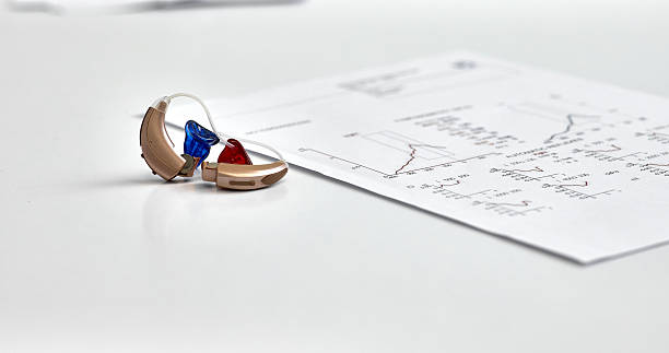 istock Left and right hearing aids lying on audiologist table near hearing test documents. Hearing check-up concept 2226511206