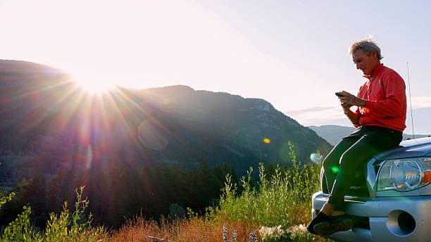 istock Mature man uses phone near vehicle, mountain peak distant 2226513376