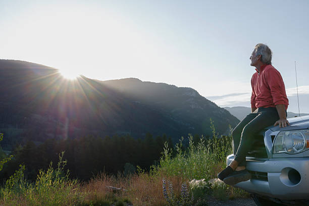 istock Mature man relaxes on vehicle at sunrise, mountain distant 2226513417