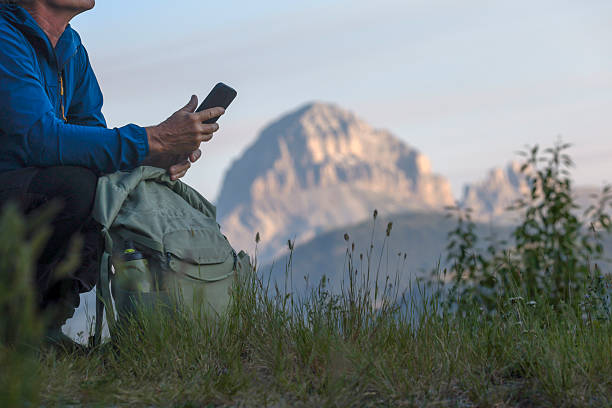 istock Crop view of mature man using mobile phone in mountain meadow 2226513702