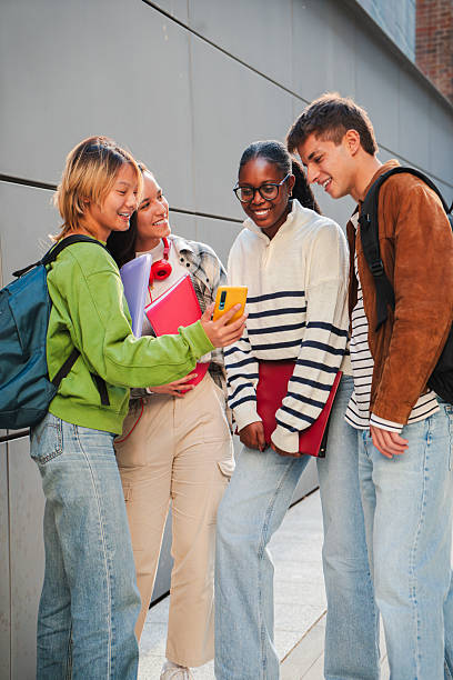 istock Vertical Group of teenage students talking on the university campus after classes. Young classmates having a friendly conversation about exams. Four friends chatting together. Guys speaking 2226514133