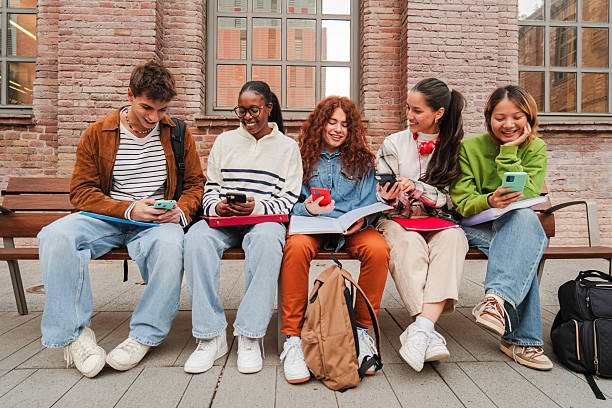 istock Diverse Group of College Students Engage with Their Smartphones While Studying Together on Campus Bench, Mixing Social Media and Academic Work Against Historic Brick Architecture 2226514654