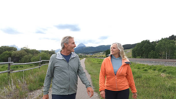 Two elderly people walking hand in hand in a Scottish forest.