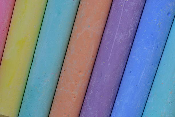 Close-up view of pastel-colored chalk sticks arranged in a diagonal pattern. Artistic texture and color variety suitable for education, creativity, or children drawing concepts.