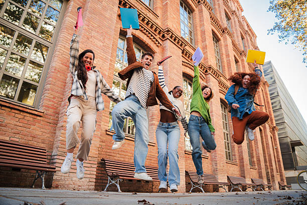 istock Excited Students Jumping Joyfully Together Celebrating Their Achievements While Holding Colorful Notebooks in Their Hands at a University Campus in a Fun and Energetic Friendship and Success 2226516605