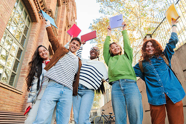 istock Group of enthusiastic students cheerfully lifting their notebooks in a triumphant academic success, embodying the spirit of teamwork and friendship during their time at school and university. 2226516801