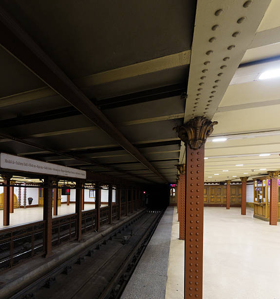 Interior of a historic Budapest Metro Line 1 (Millennium Underground) station with riveted columns and vintage design elements.