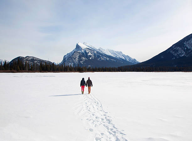 Canada Alberta Canadian Rockies ..Banff National  park young couple walking on frozen lake.