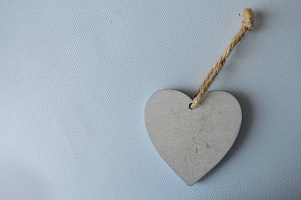 istock hand holding a plain wooden heart-shaped ornament with a rope loop, blank surface for diy, text, or holiday decoration, isolated on light background 2226521351