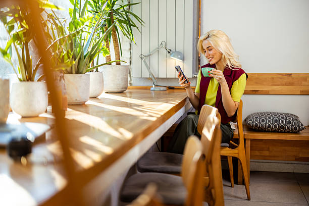 istock Young woman using mobile phone and drinking coffee in a cafe 2226524406