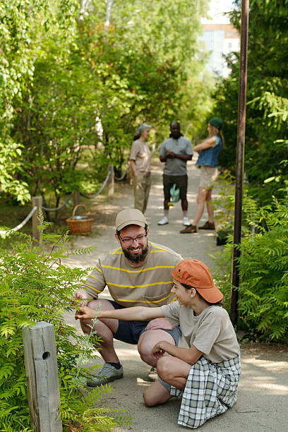 istock Caucasian Middle Aged Man and Child Exploring Plants in Park with Diverse Group 2226528010